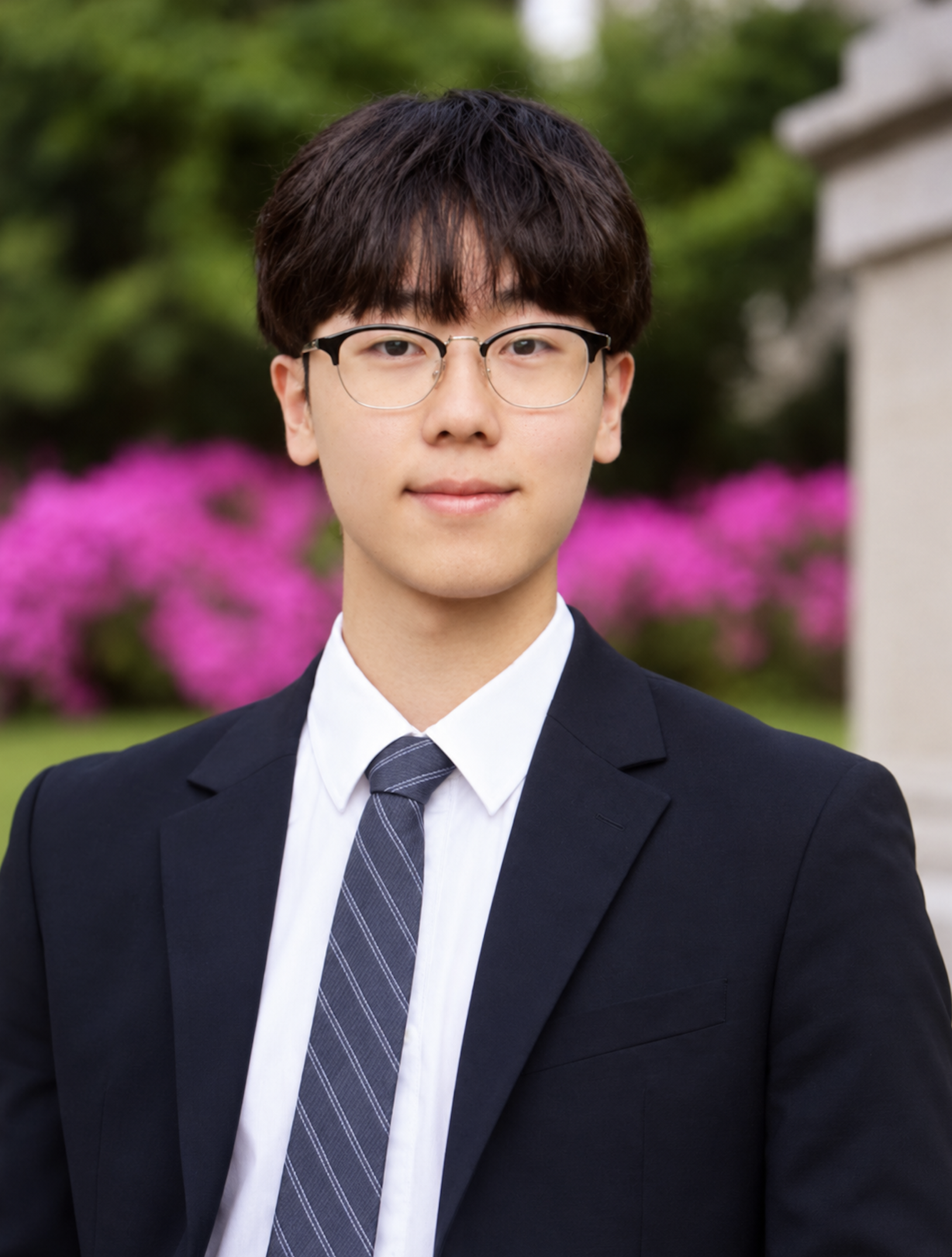 Portrait of Aaron Kim outdoors, wearing glasses, a dark suit, and a striped tie.