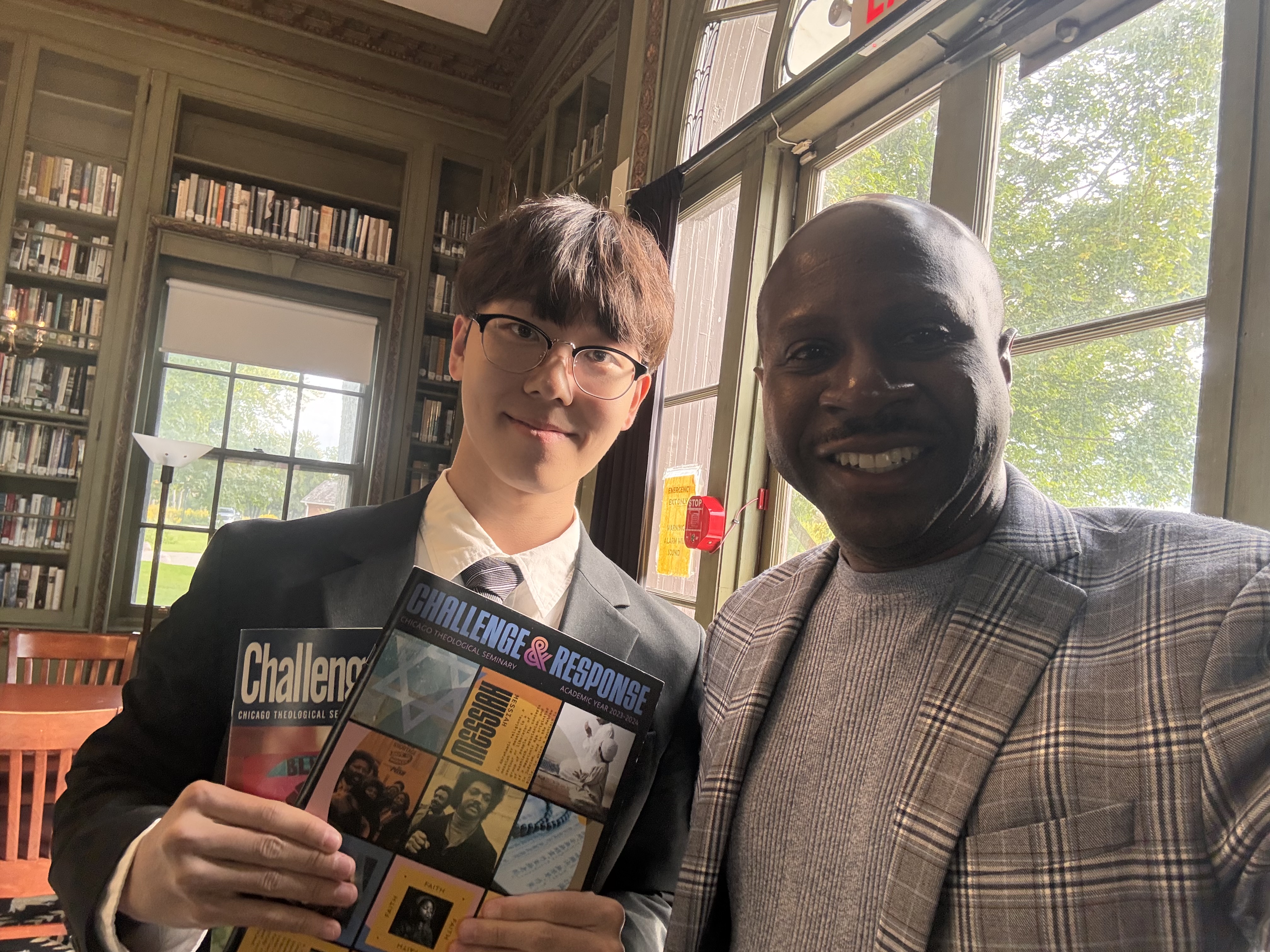 Two people standing together indoors with Chicago Theological Seminary publications.